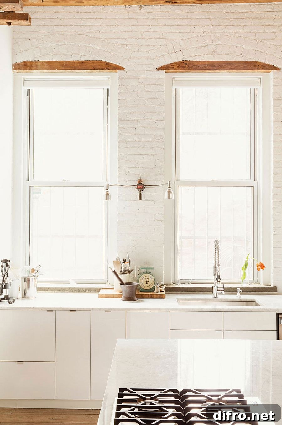 Kitchen in white with exposed brick walls and large windows