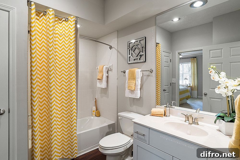 Curtain with chevron stripes brings yellow to the modern gray bathroom [Photo Credit: Valerie Ryan Photography / RealPage, Inc]
