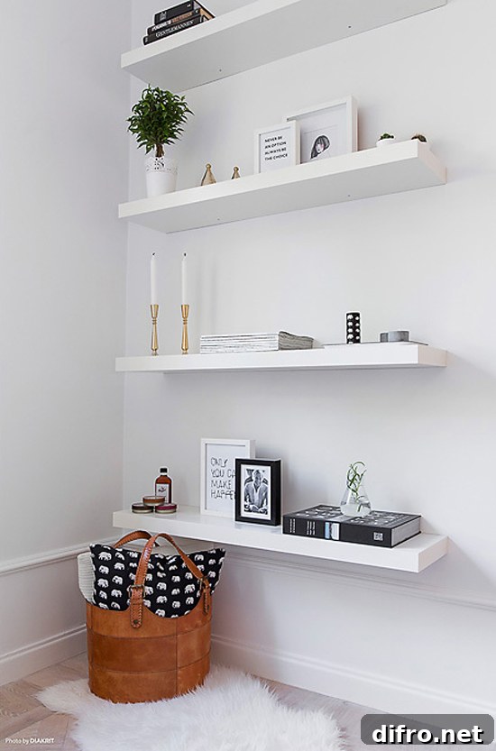 Floating Shelf Ideas to Style Your Living Room 5 Four white floating shelves with picture frames, candles, and books.