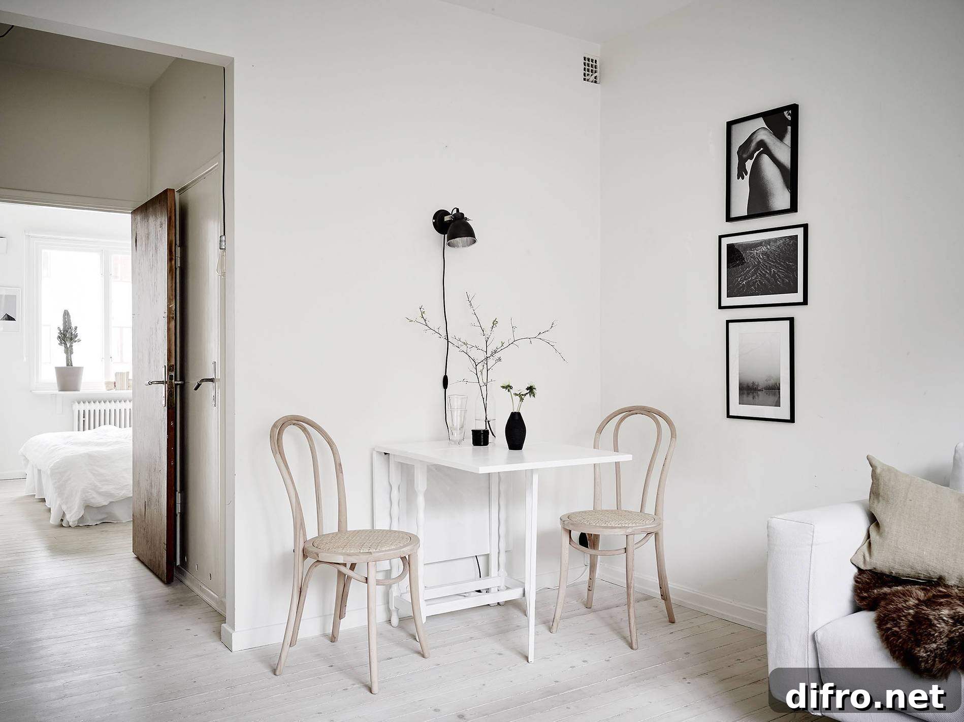 A minimalist white room with a wooden table and two chairs.