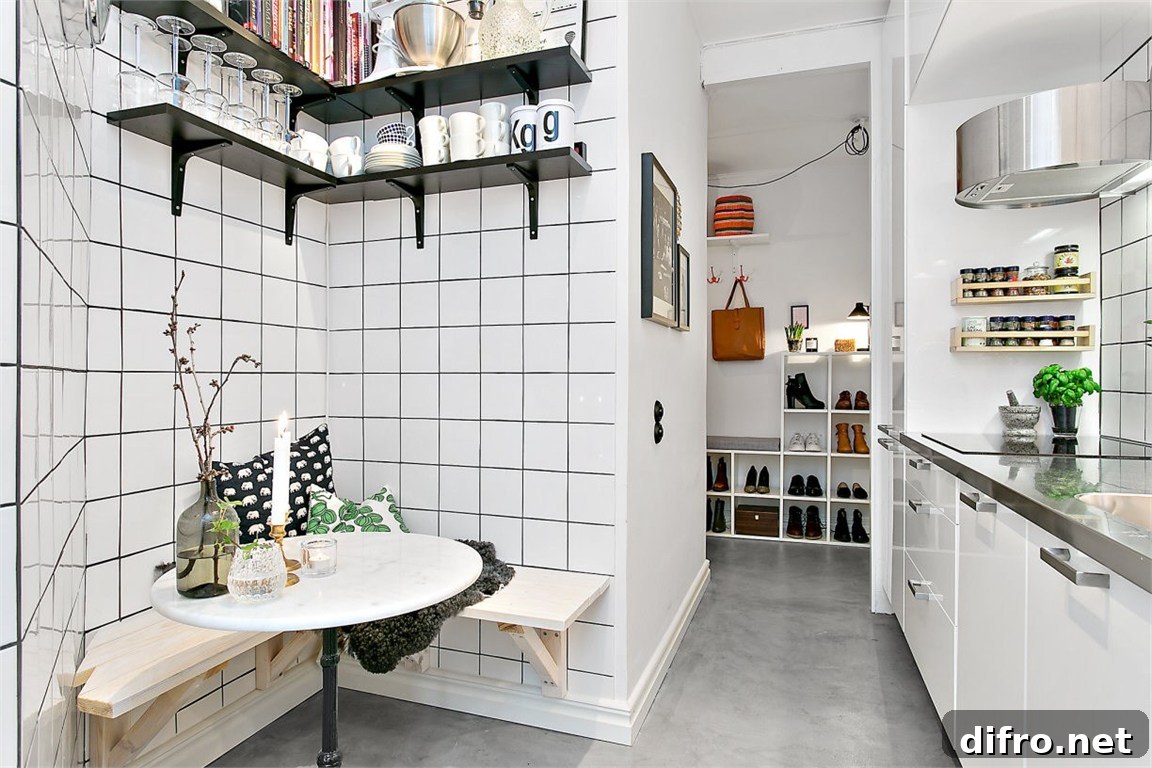 A small kitchen with white tile walls and shelves. Wall-mounted bench seats with a round table.