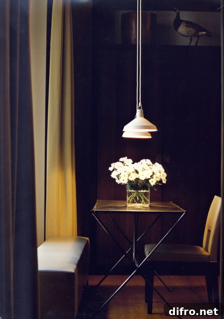 A wooden table with a vase of white flowers in the center is surrounded by two chairs.