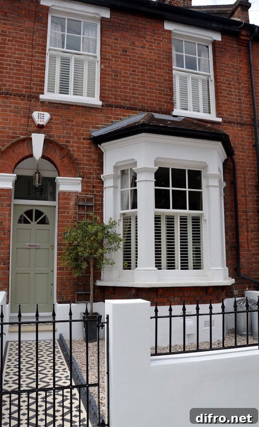 Red brick house with white window trim and fencing.