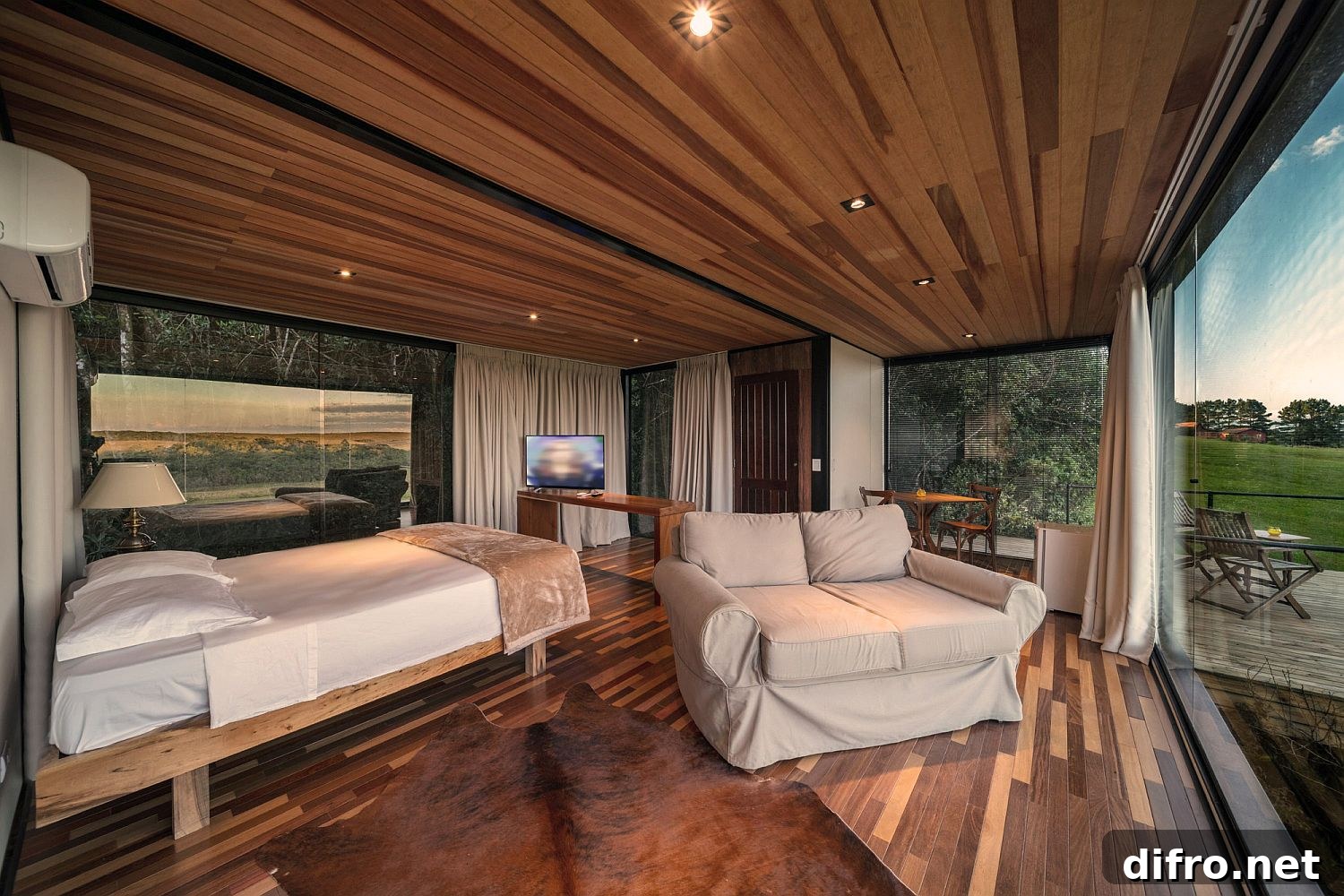 Wood and glass bedroom of the cabin with a wide view of the landscape