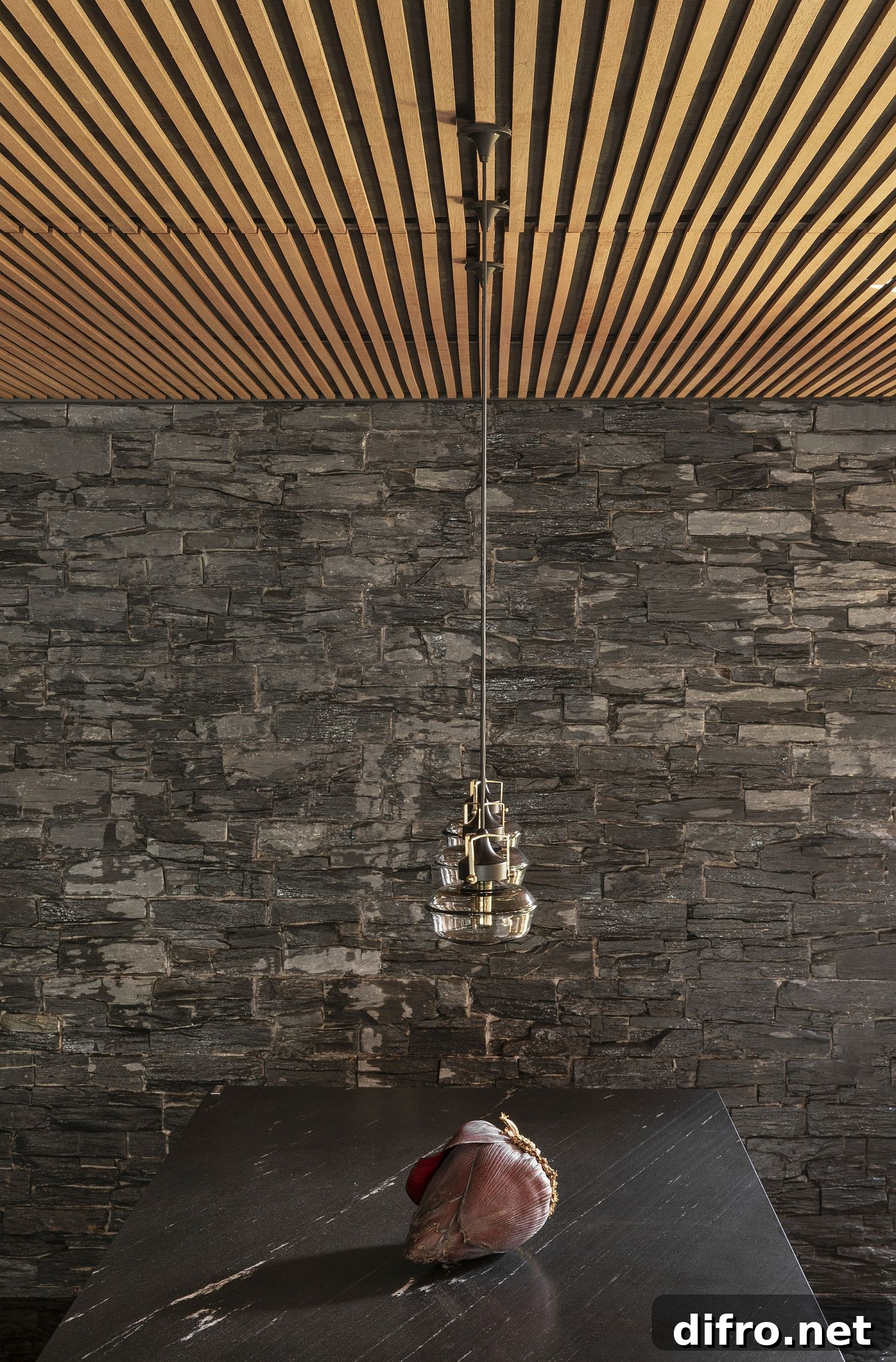 Dining room with wooden ceiling and stone wall backdrop