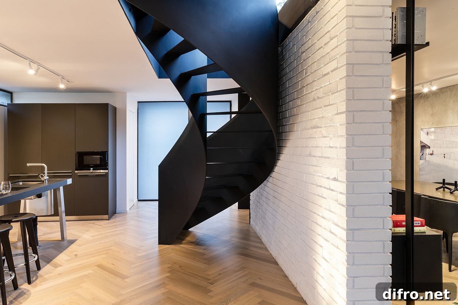 Brick wall divides the lower level offering a white backdrop for the spiral staircase