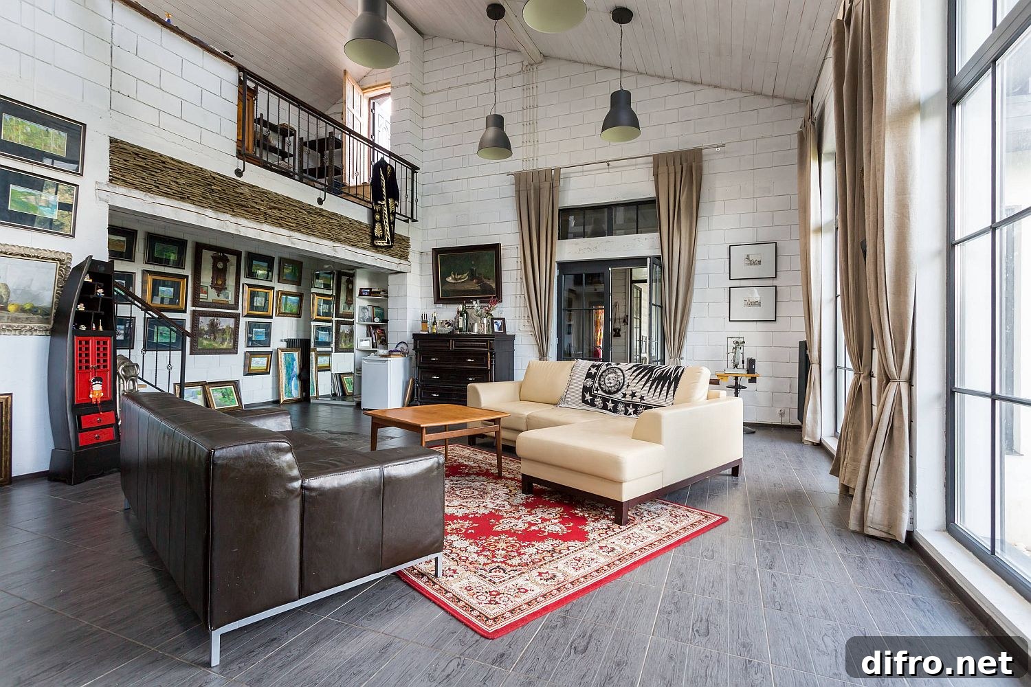 Double-height living-room with white painted brick wall on one side and gallery wall