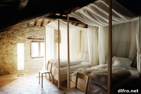 Twin curtained canopy beds in a bright Italian-inspired room