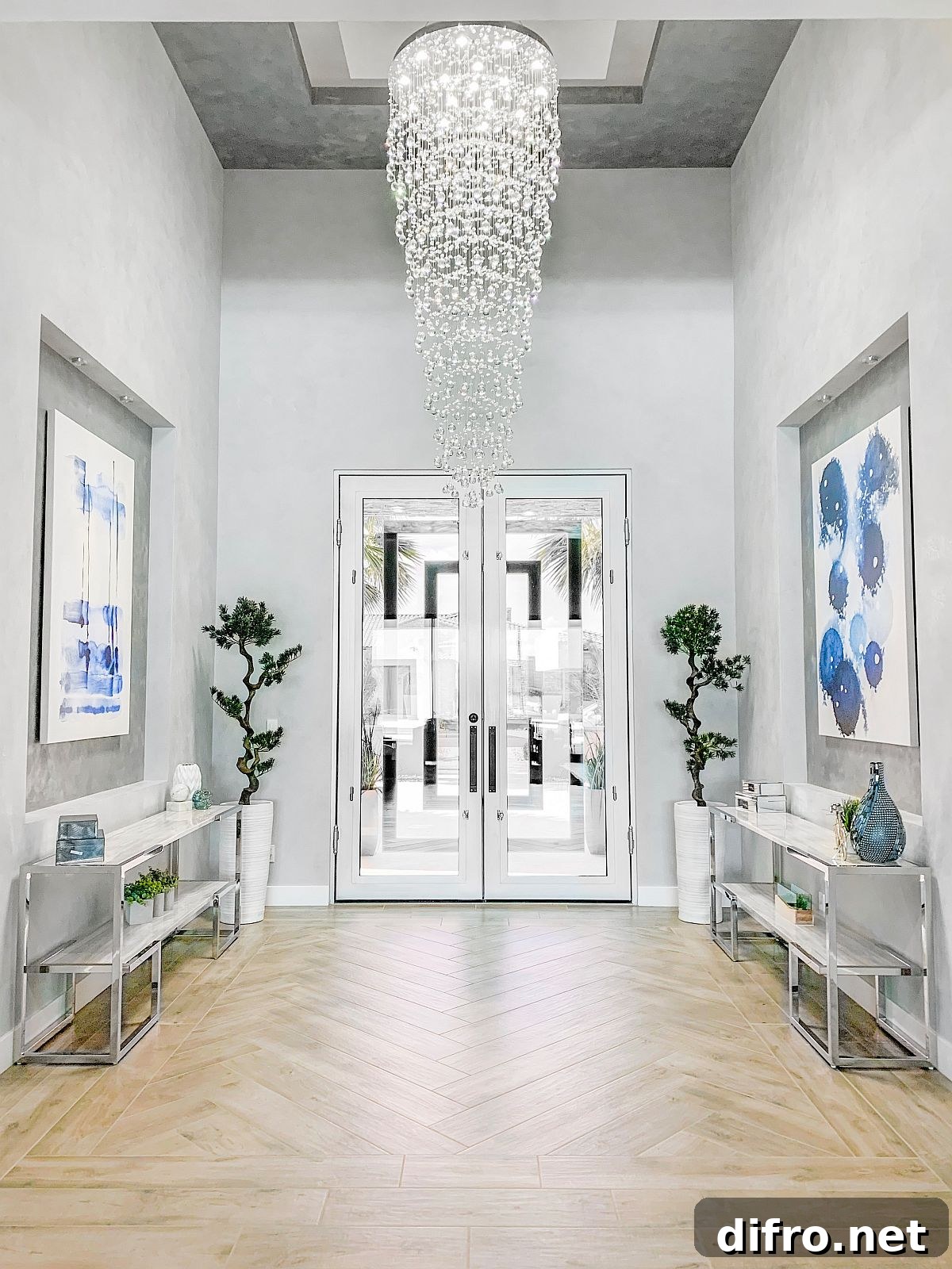 Cascading chandelier in large white entry with greenery