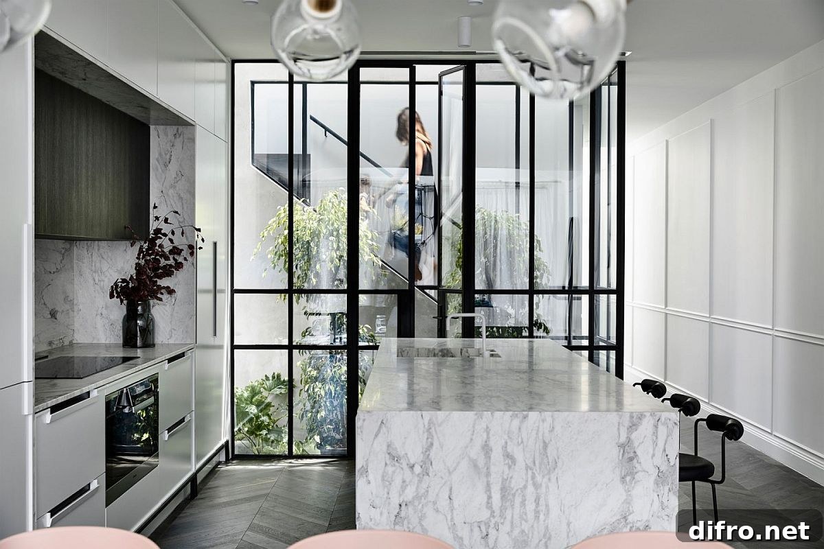 White kitchen with dark-framed glass wall overlooking an atrium