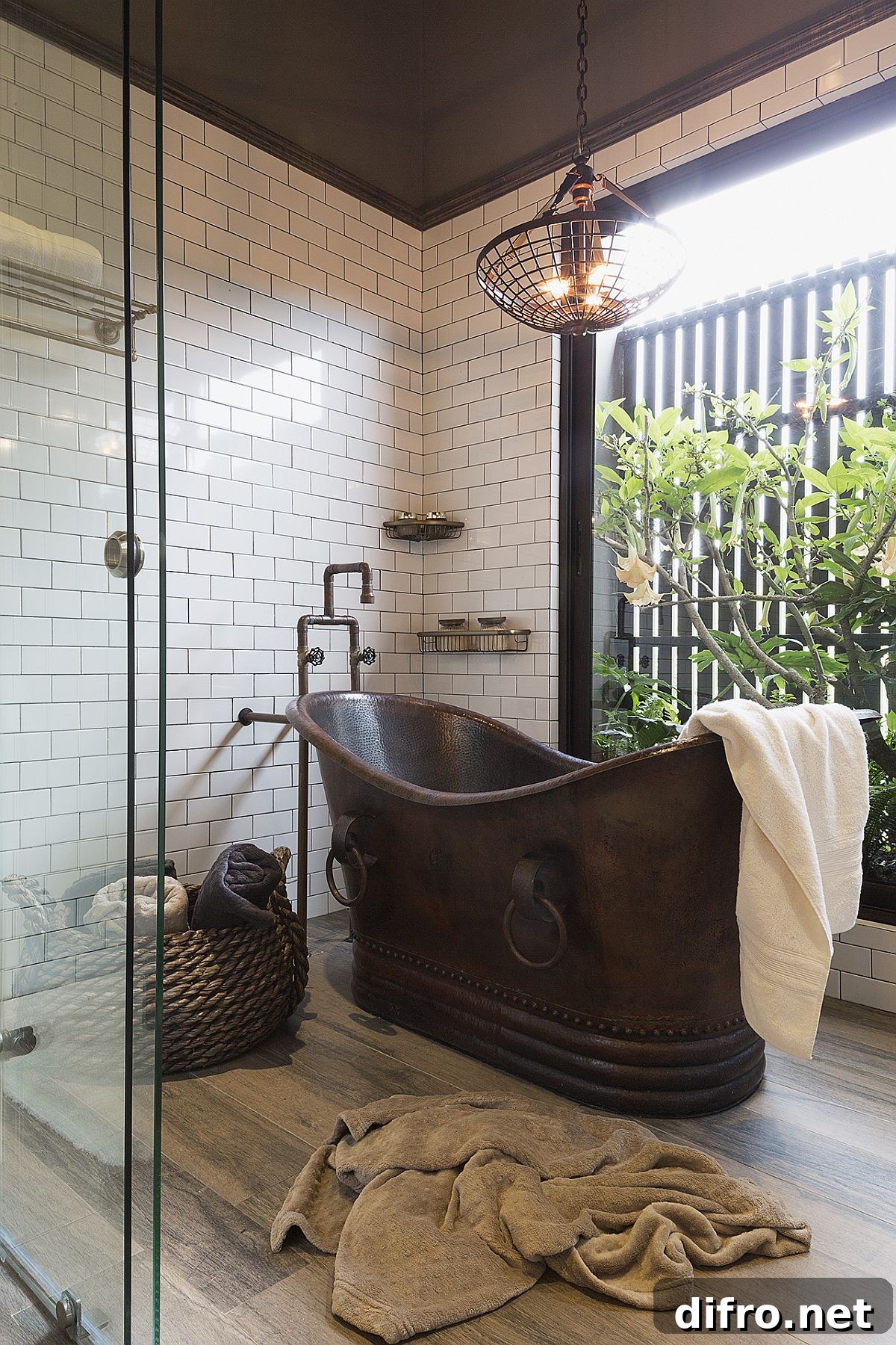 Copper bathtub with glass walls and greenery in the bathroom