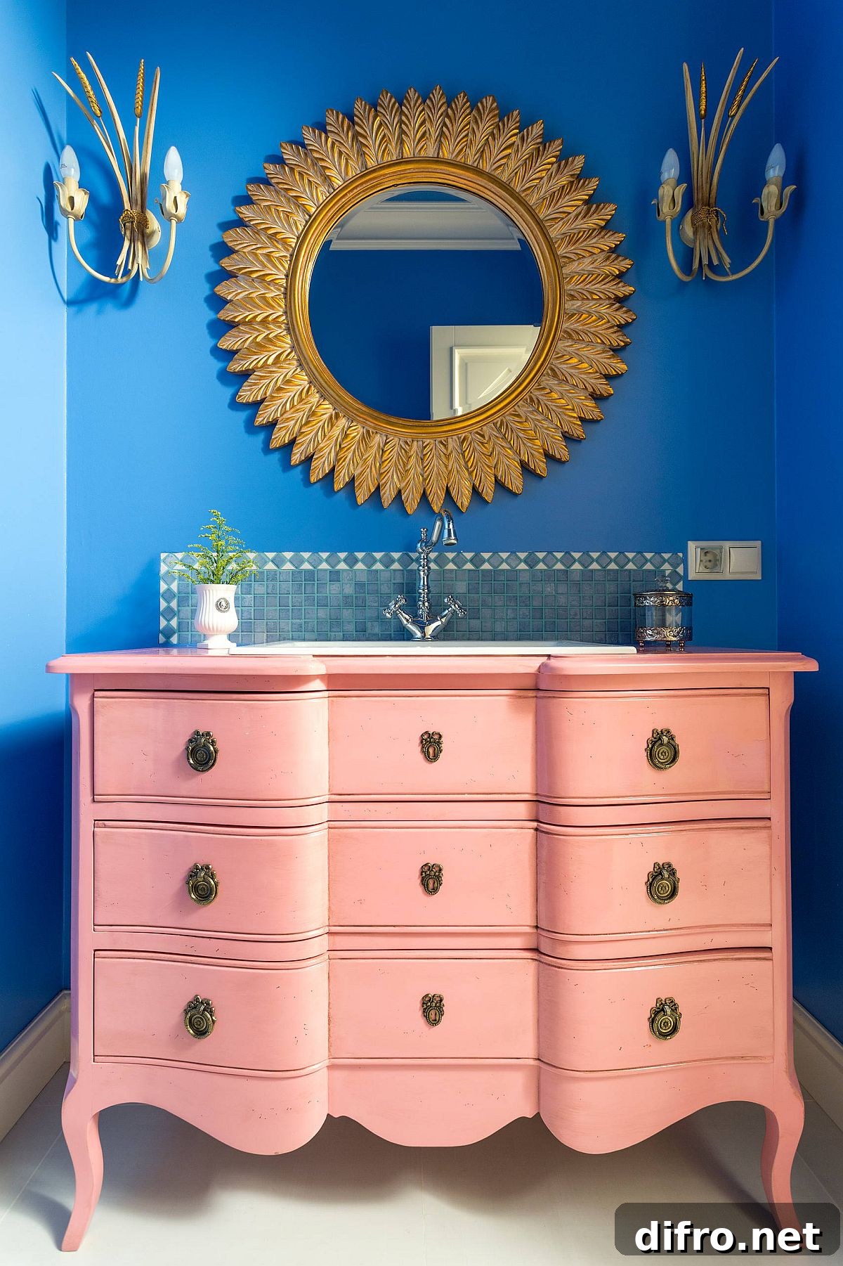 Blue bathroom with a light pink vanity and gold mirror