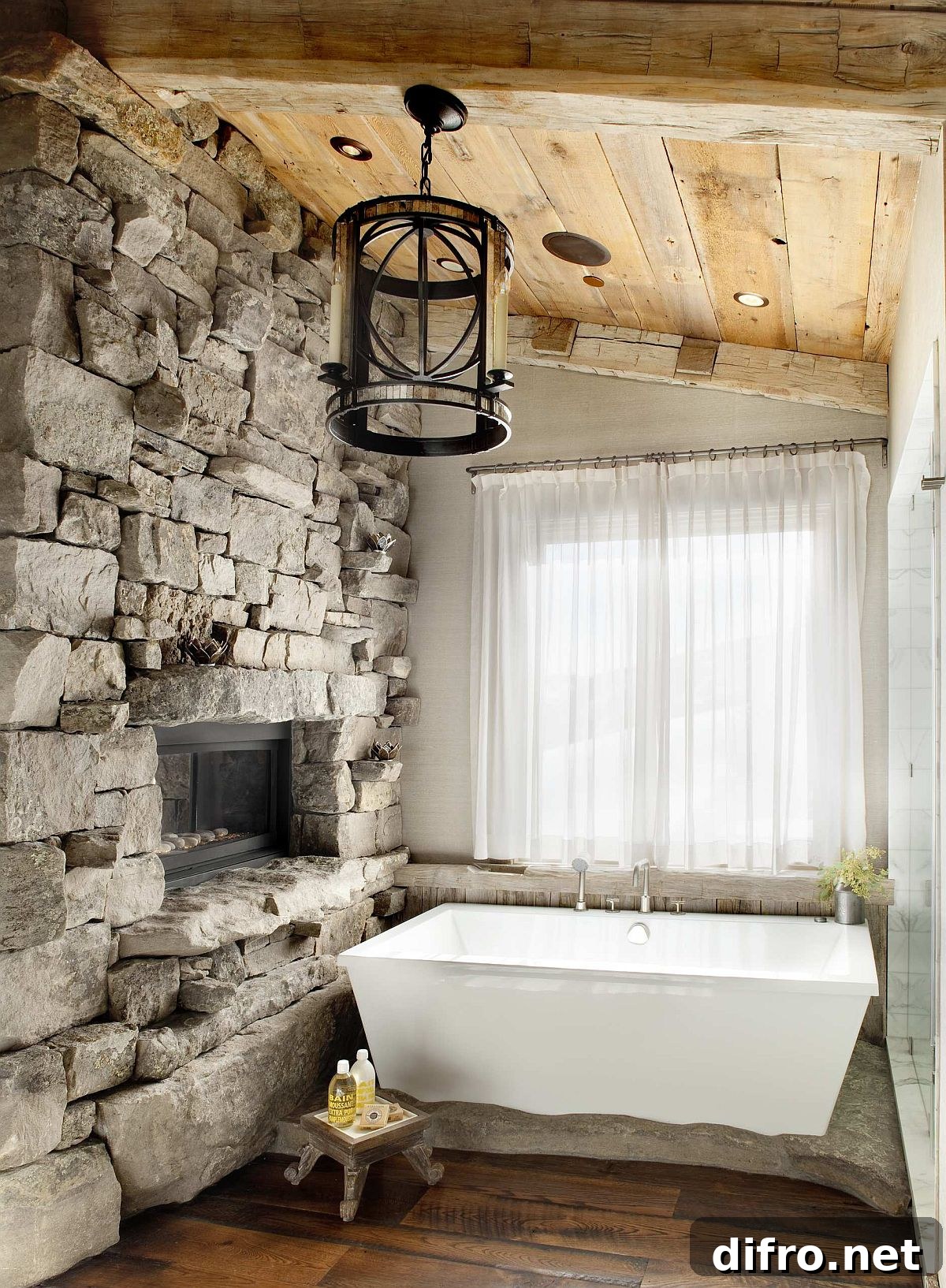Rustic bathroom with stone wall, fireplace, and white tub