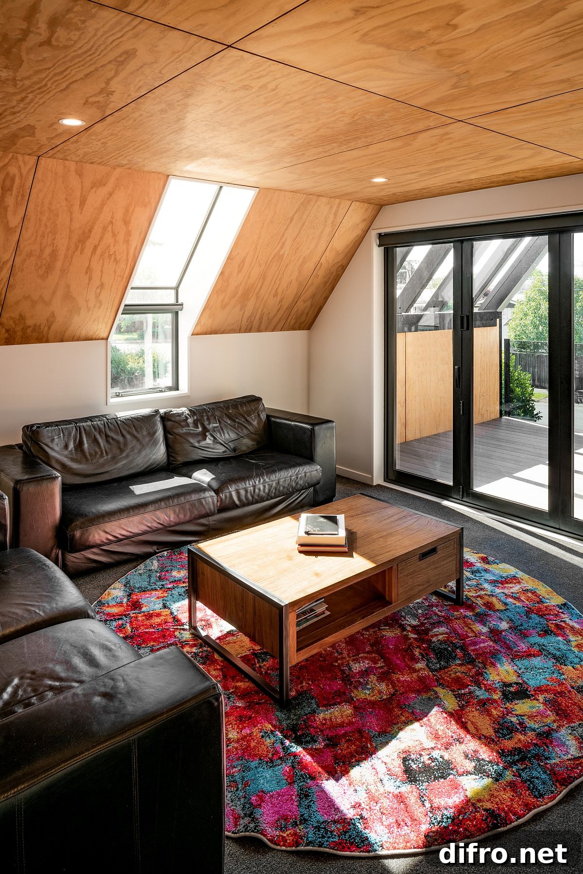 Cozy attic style living area with wooden ceiling and colorful rug