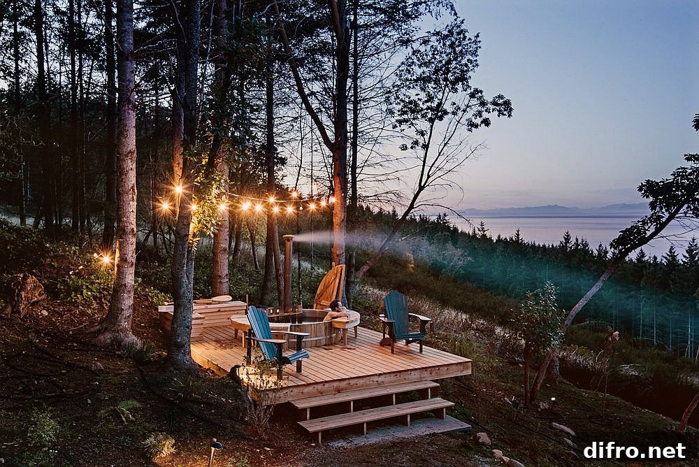 String lighting illuminates the deck overlooking the sea and forest
