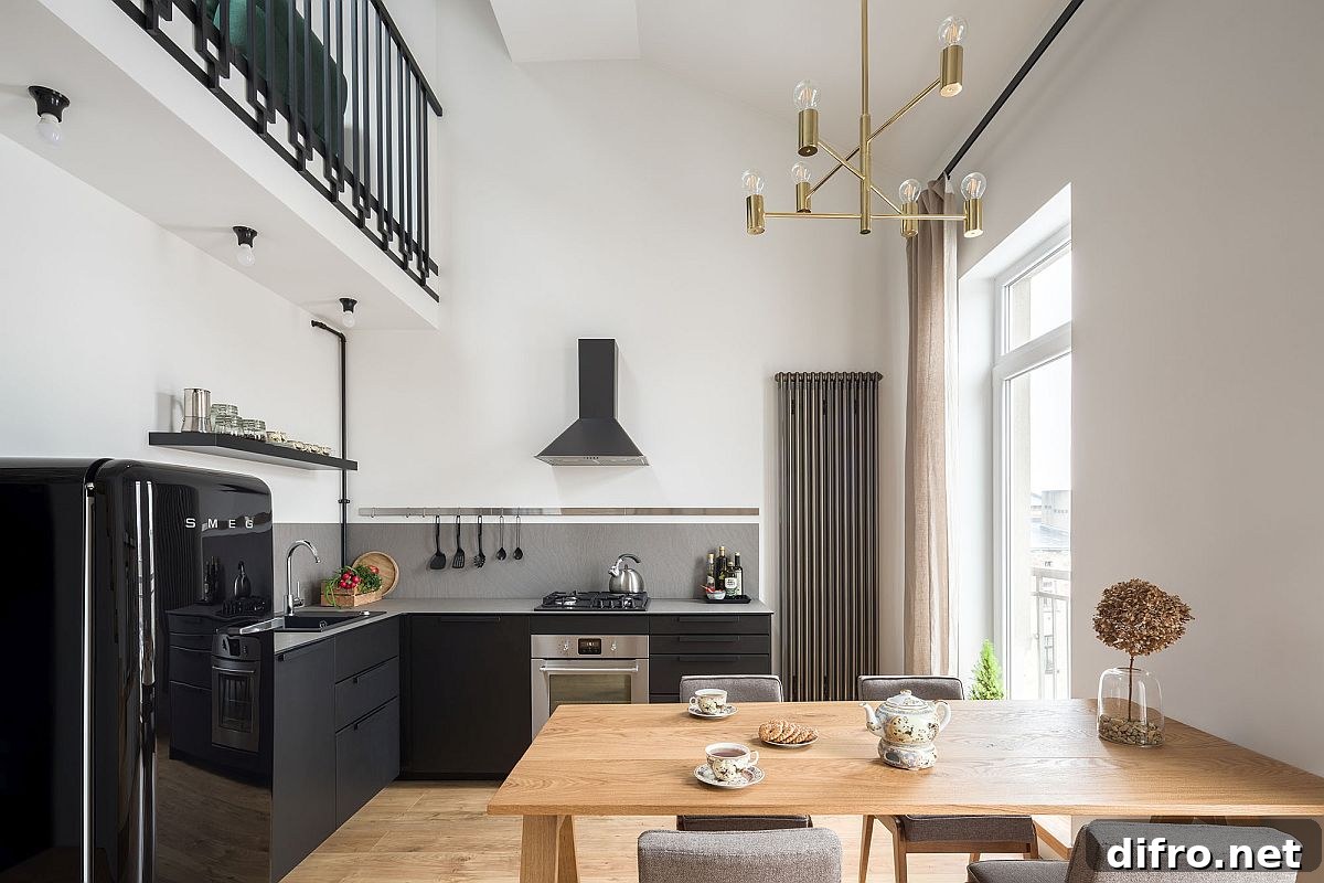 Double height dining area of the house with kitchen in black next to it