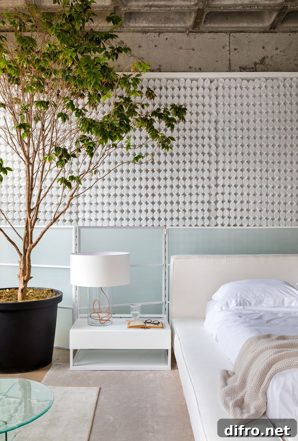 Large indoor plant brings visual contrast to a bedroom in white and muted colors