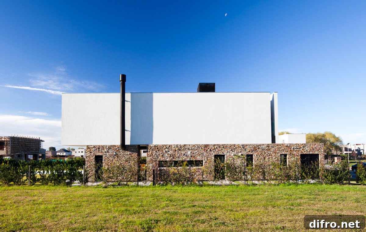 Stone plinth wall around the house provides a sturdy base for the cantilevered upper level