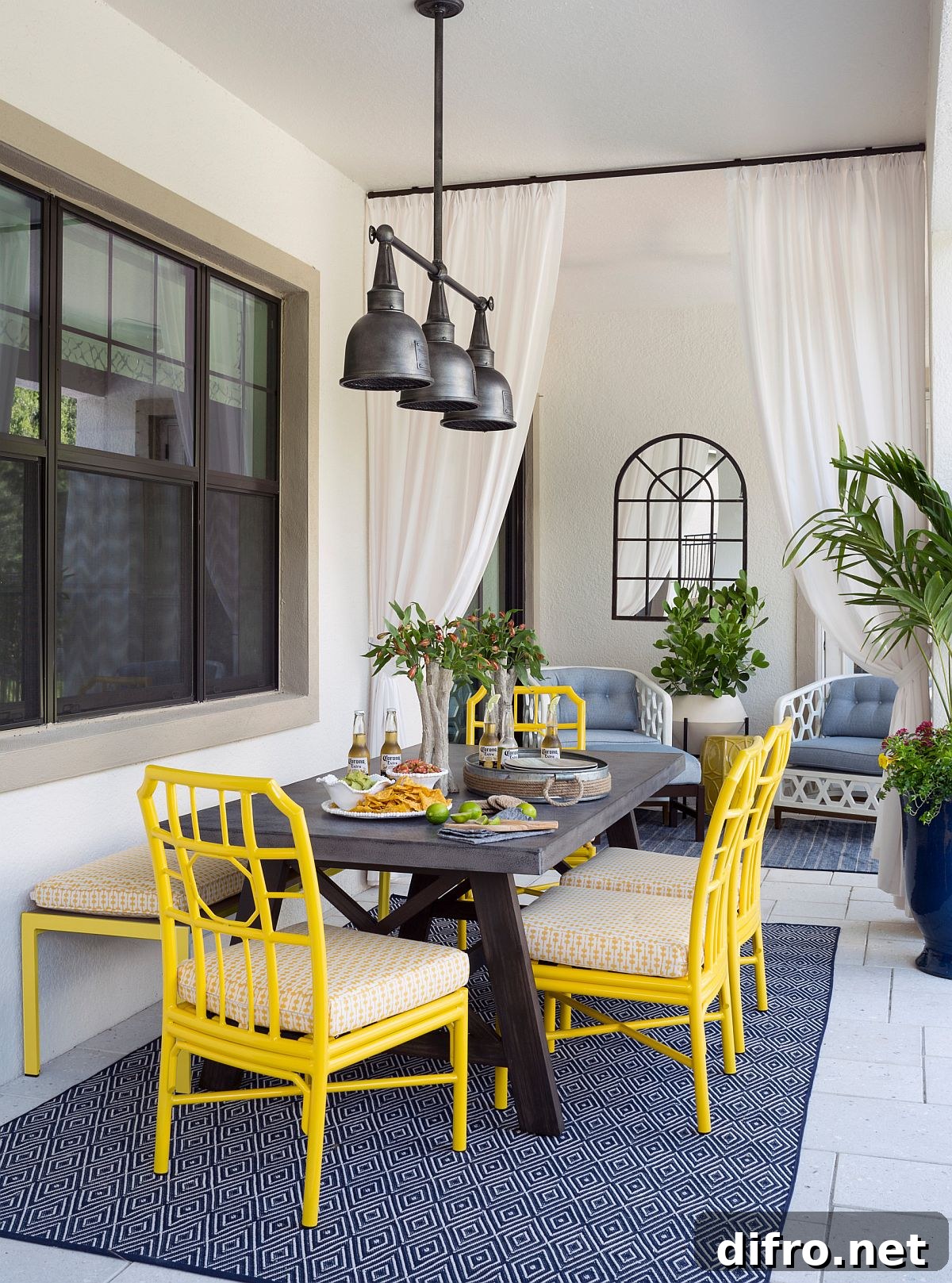 Yellow chairs and blue rug bring color to porch dining