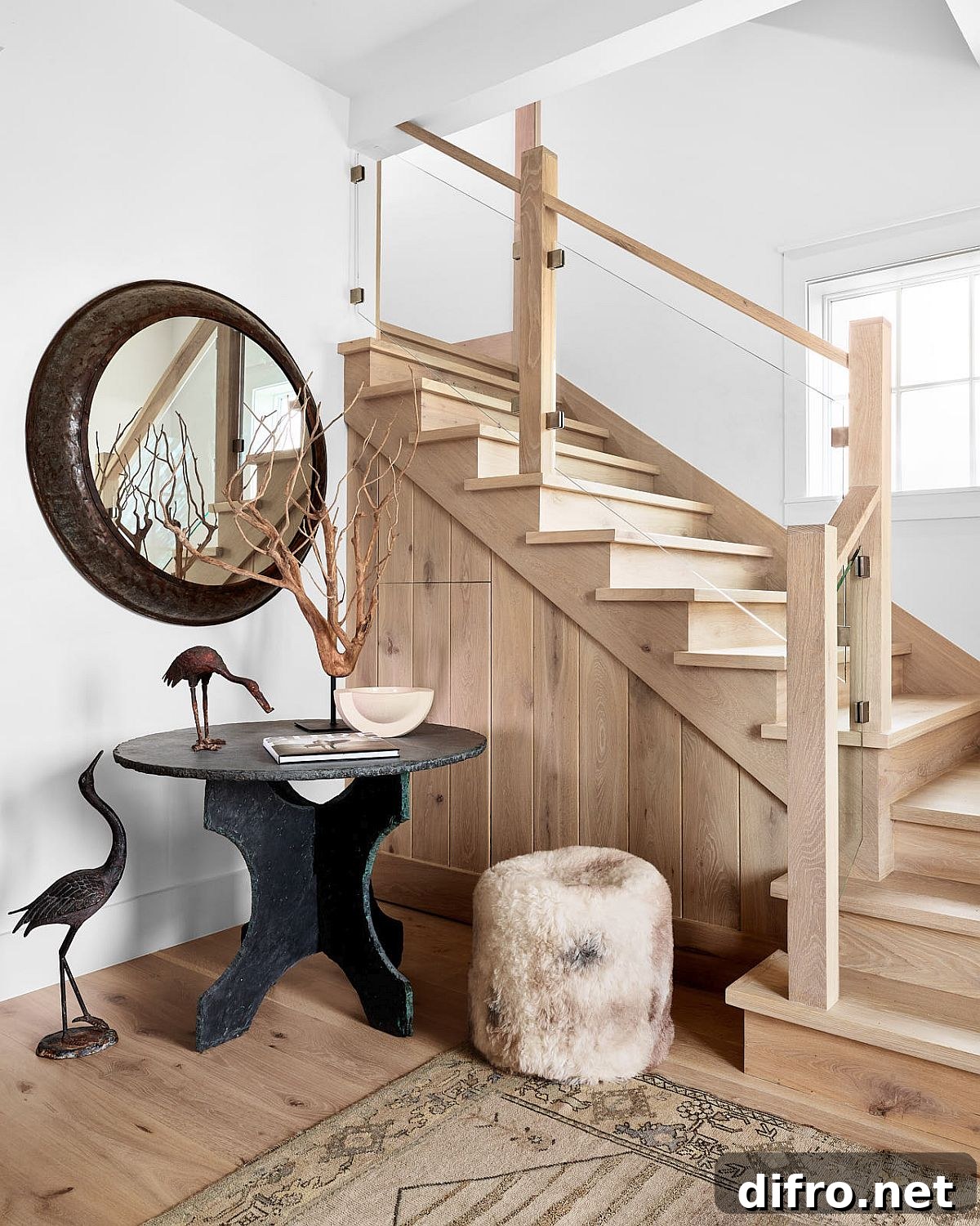 Beach style entry to the bungalow with a vintage console table, round mirror and staircase leading to the upper level