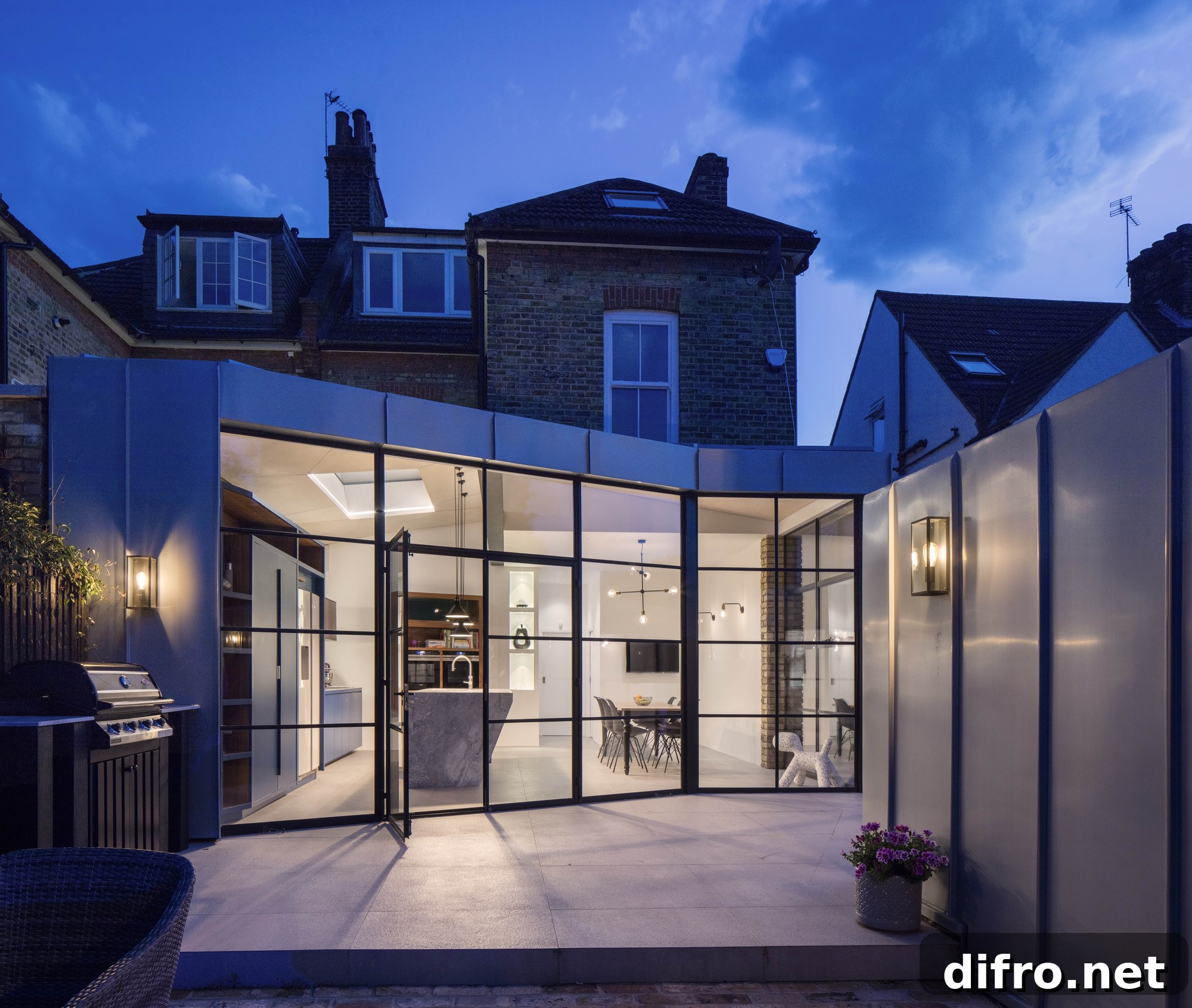 Dark-framed glass walls connect the kitchen and dining area with the garden