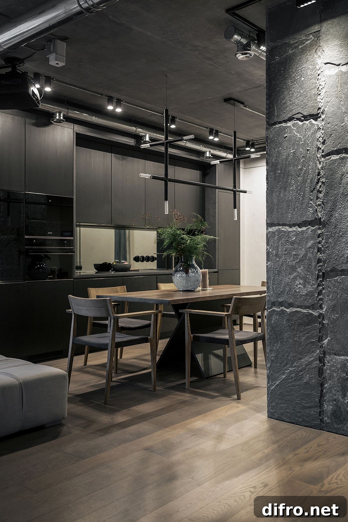 Kitchen and dining area of the apartment with lovely black cabinets and unique lighting fixtures
