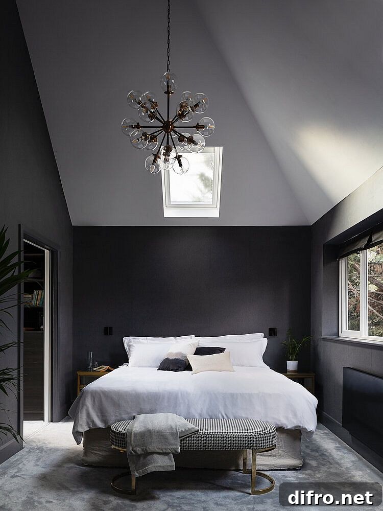 Double-height master bedroom in gray and white with sloped ceiling and skylights