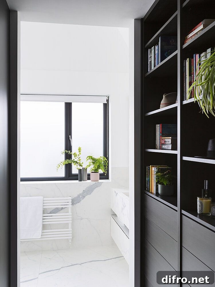 Dark bookshelf and cabinets in wood flank the corridor leading to the bathroom