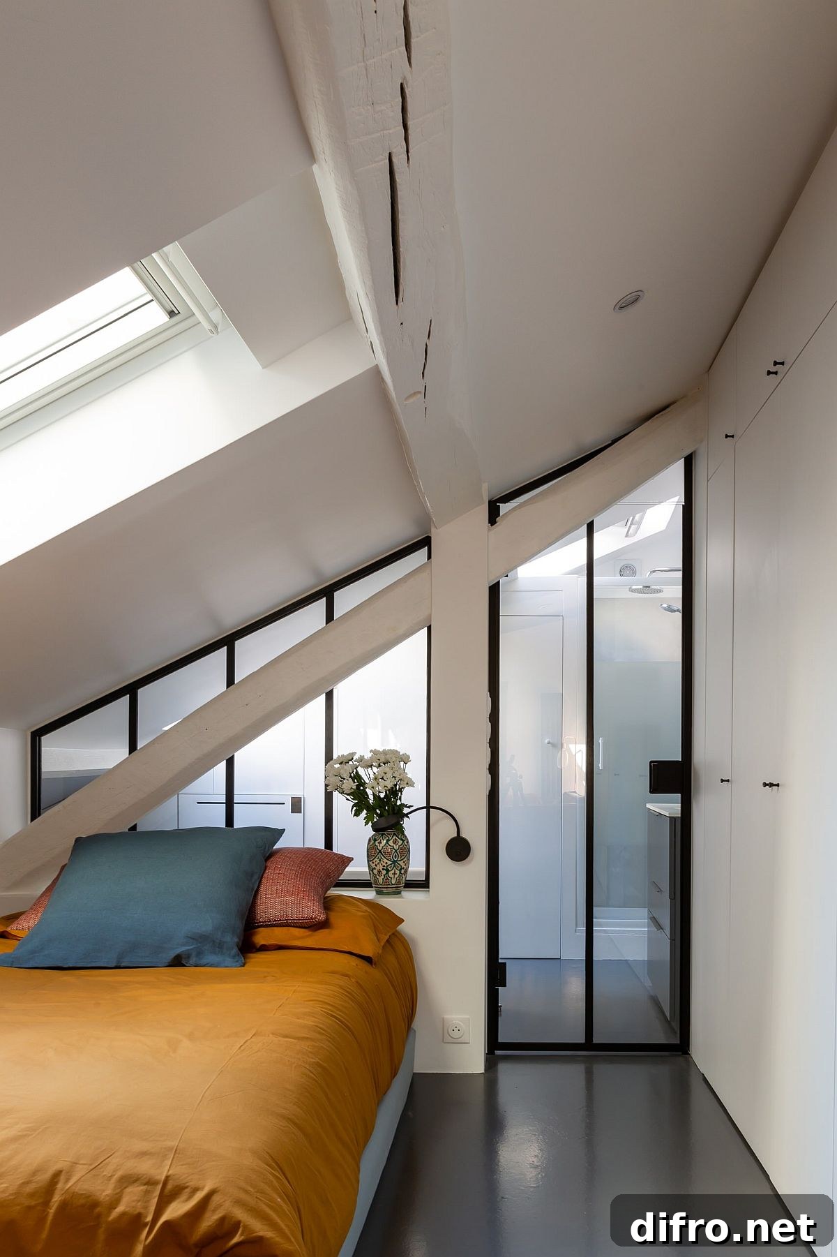 Light-filled French apartment bedroom with skylights and colorful bedding