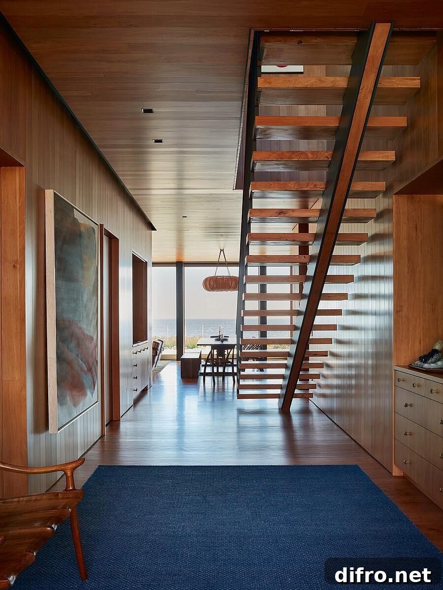Area rug in blue brings color to this spacious beach style interior covered in wood