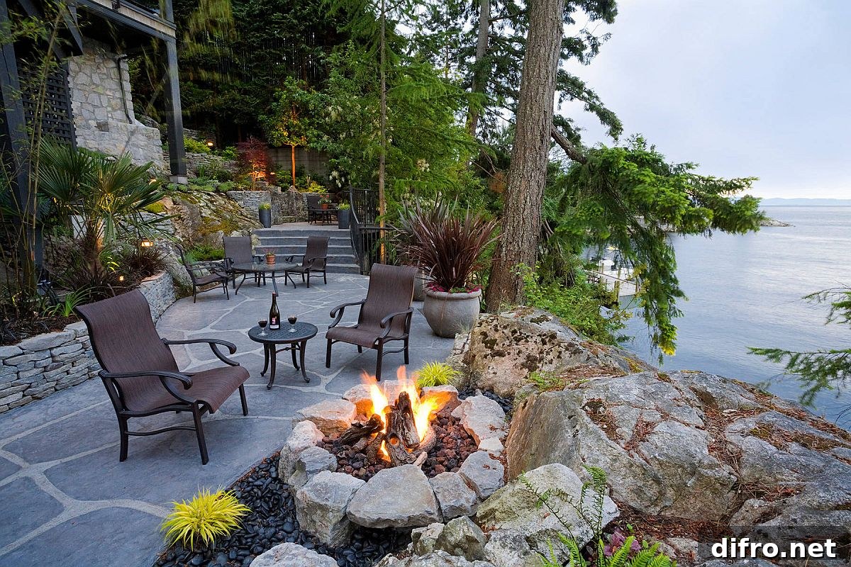 Rustic waterside terrace with fireplace and seating