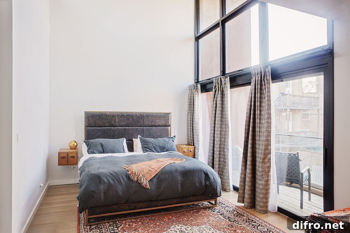Master bedroom of the home on the upper level with glass walls that usher in ample natural light