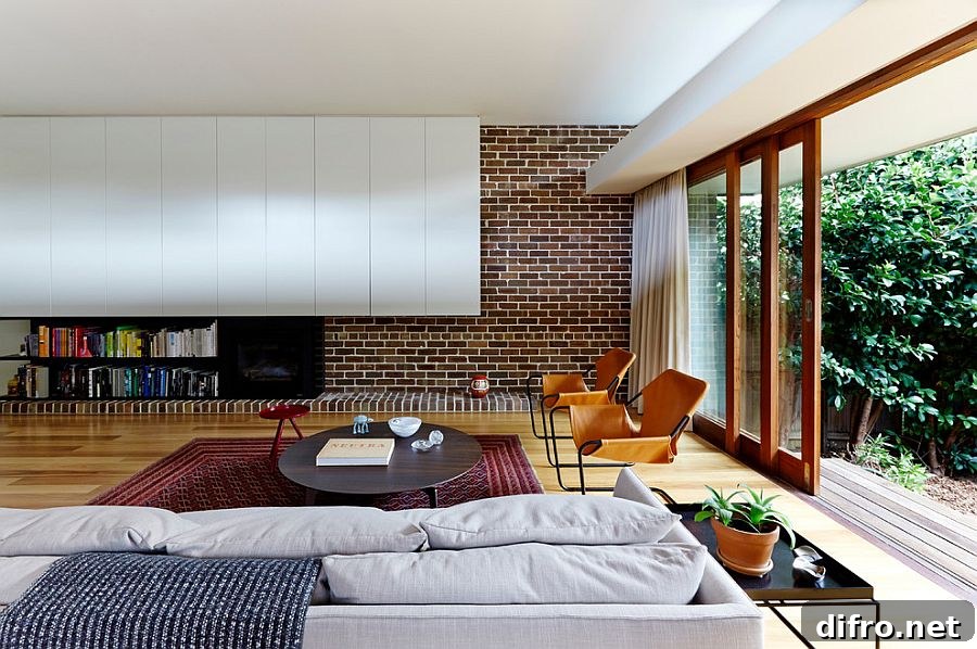 Modern living room mixes brick wall with contemporary shelves in white [Design: Downie North Architects]