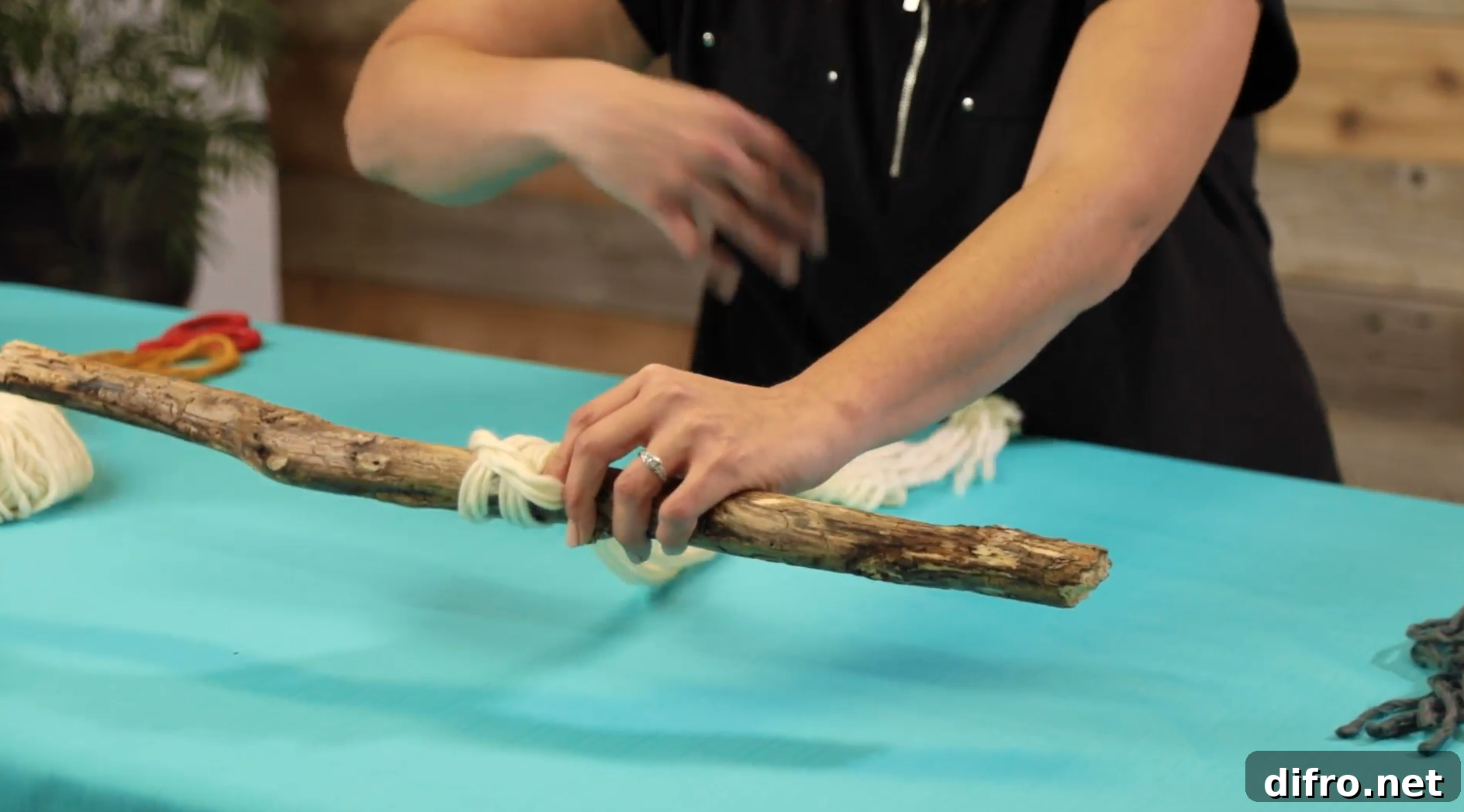 tying white yarn to stick for knot and tassel project