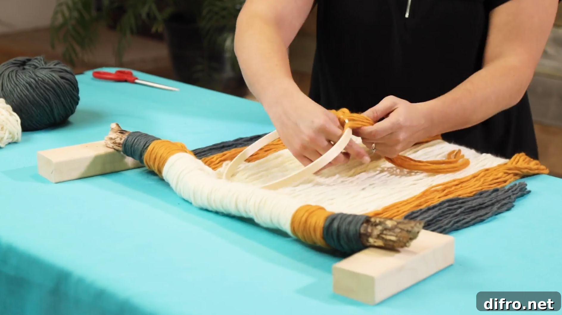 tying yellow yarn to embroidery hoop for knot and tassel
