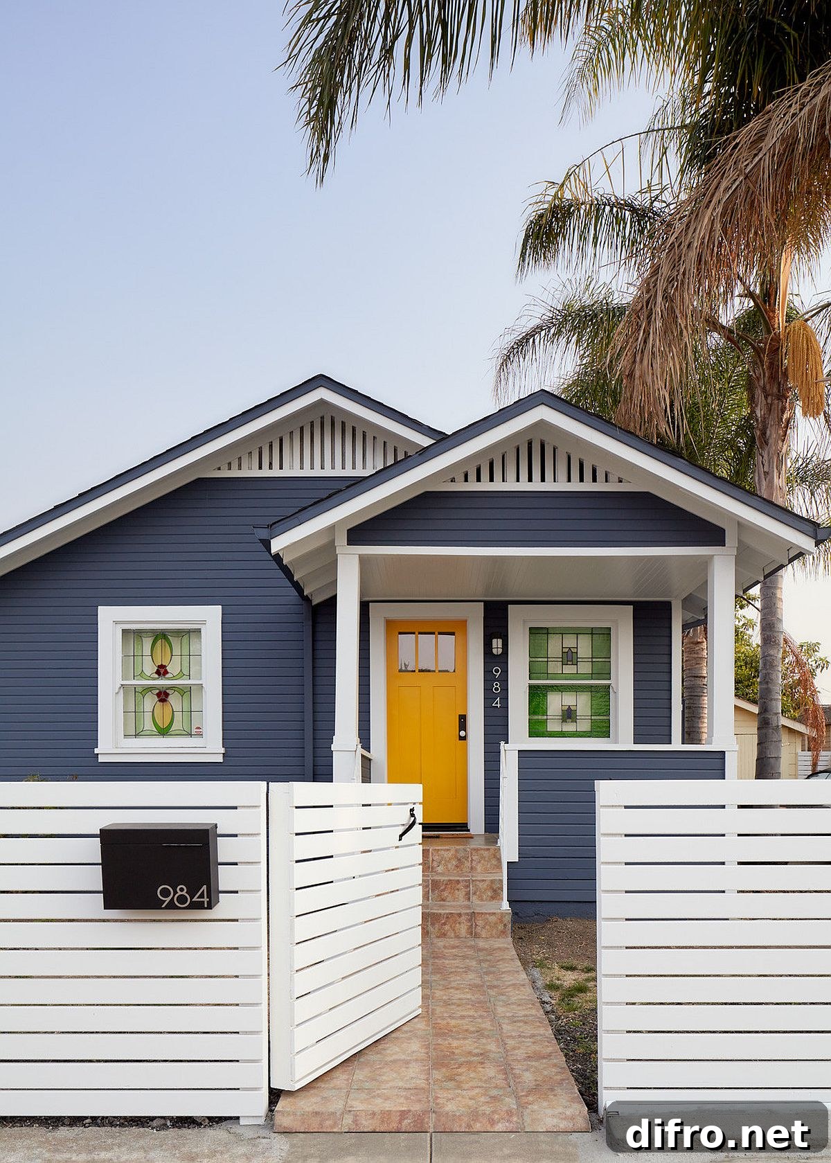 Modern home facade in bluish-gray and white with a dark yellow door