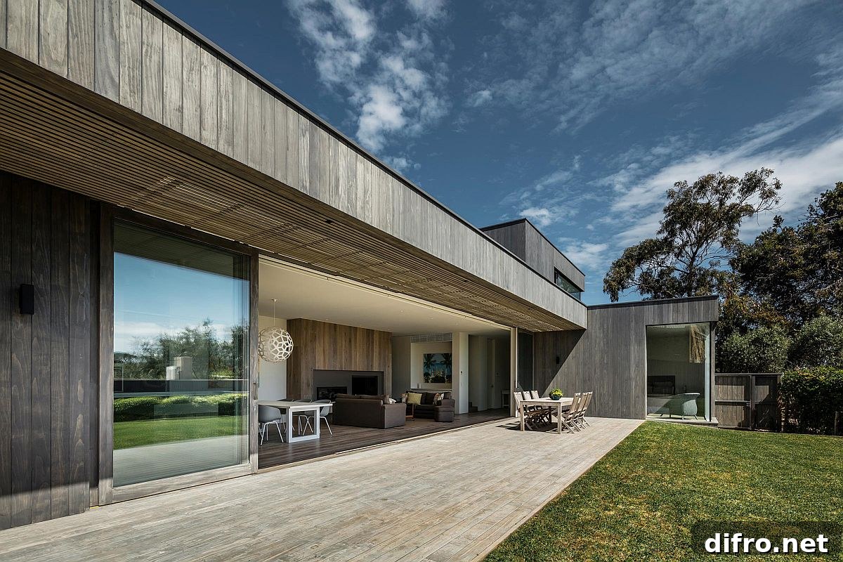 Sliding, stackable glass doors with a wooden frame connect the living area with the deck outside