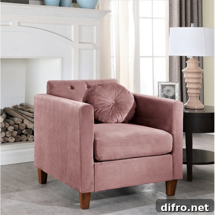 Rose color armchair with round cushion beside a table and a lamp