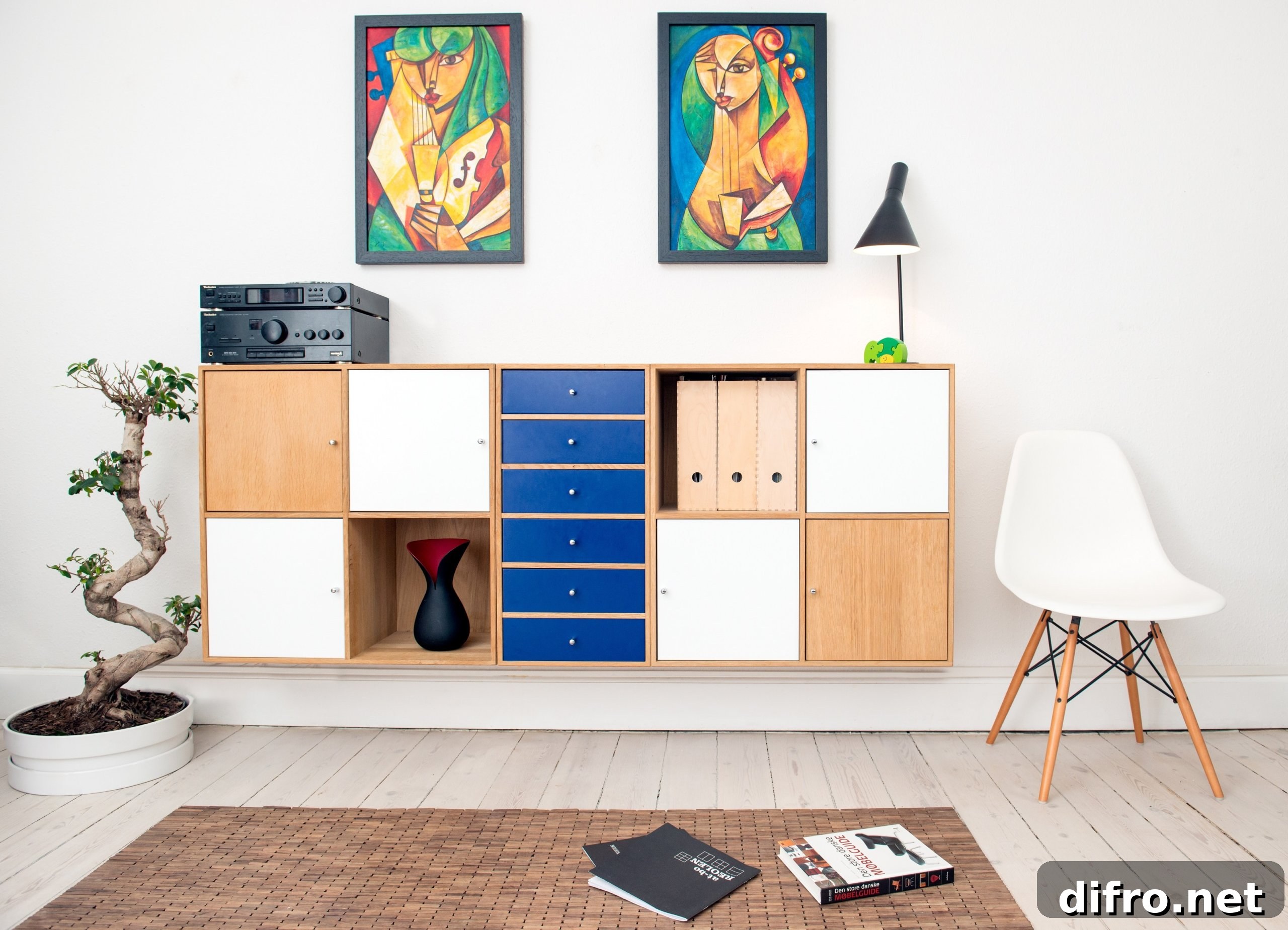 Two paintings above cabinet with blue drawers