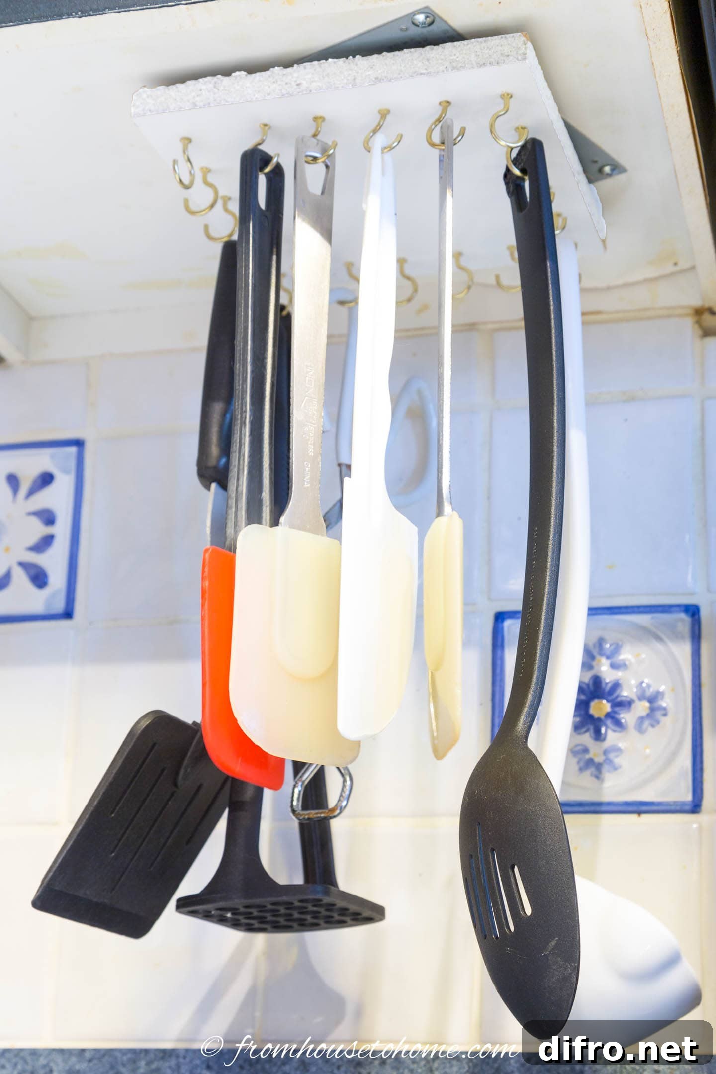 utensils hanging under kitchen cupboard on gold hooks