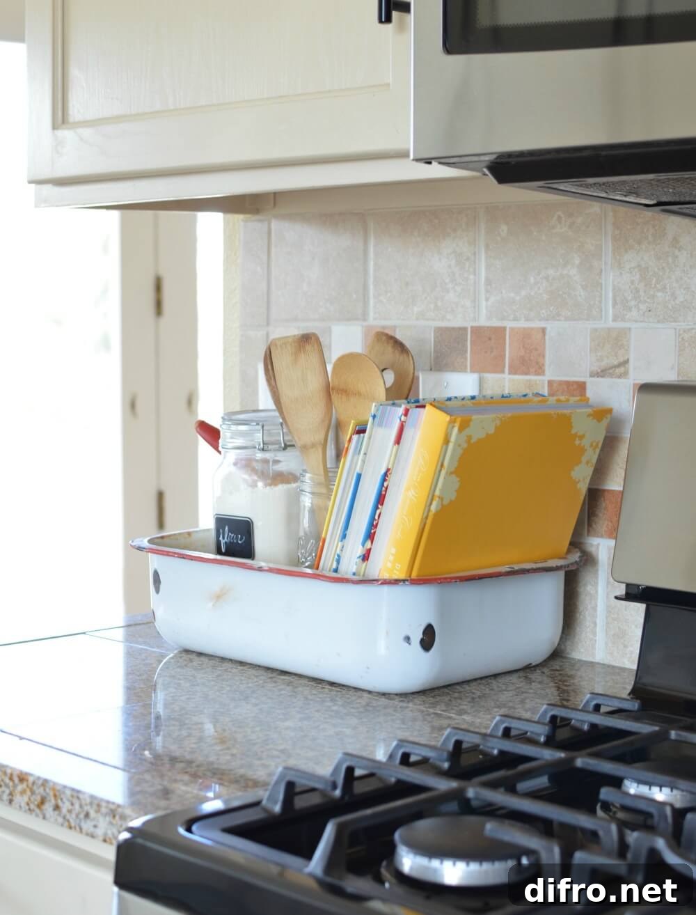old vintage washpan holding cookbooks on granite countertop next to stove