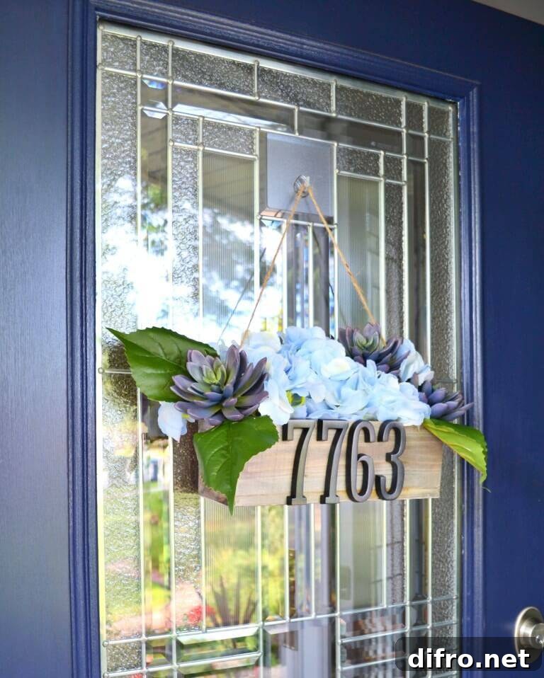 decorative planter box with faux flowers house numbers hanging from blue front door