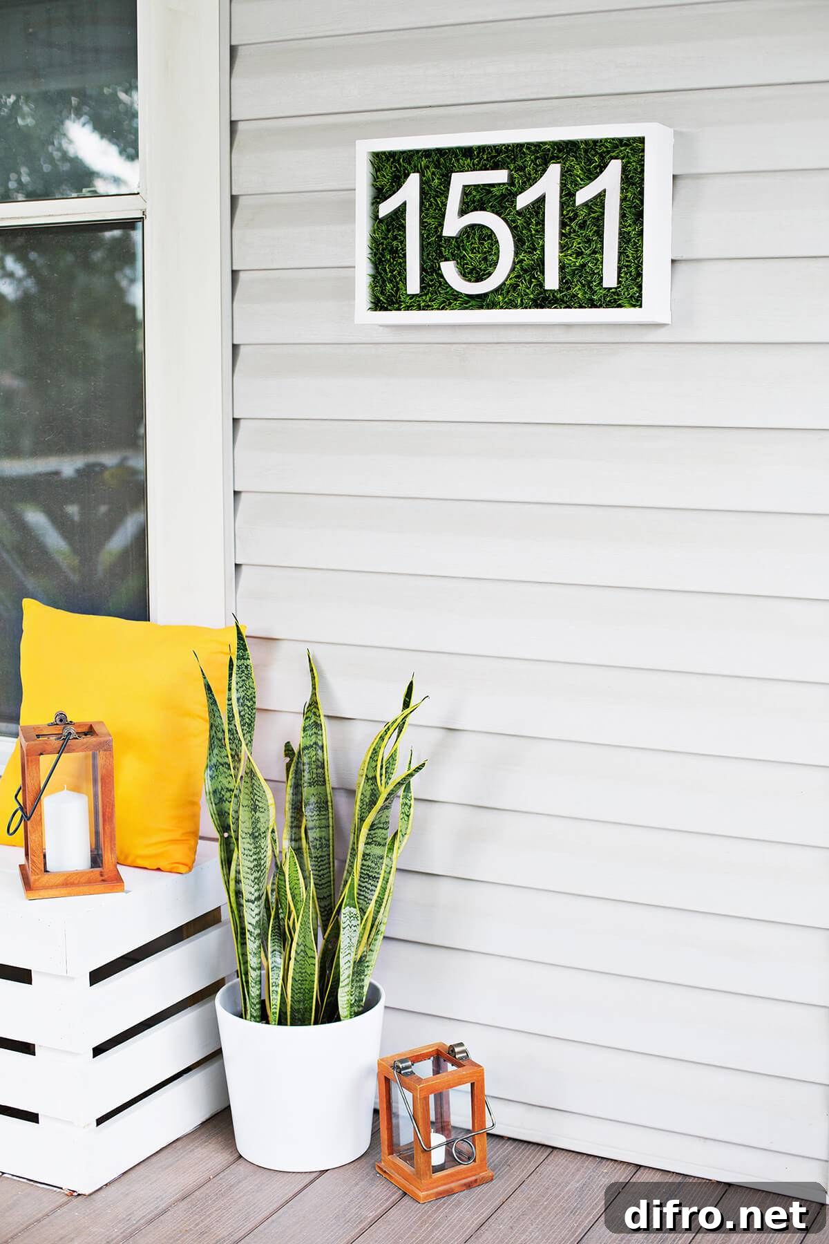 patch of grass house number sign on white siding with yellow pillow snake plant lanterns