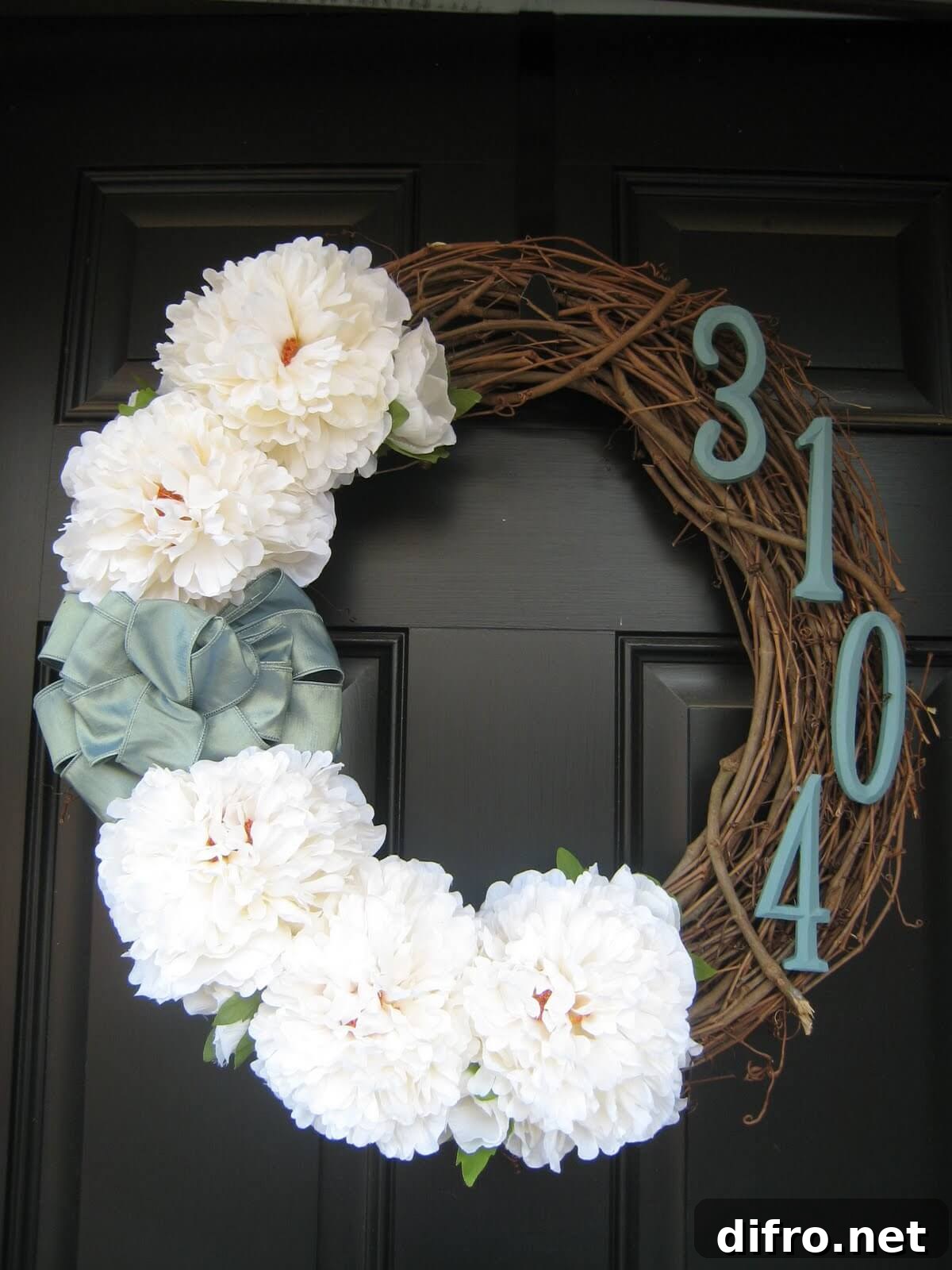 close up of wreath on front door with house numbers and white flowers blue ribbon