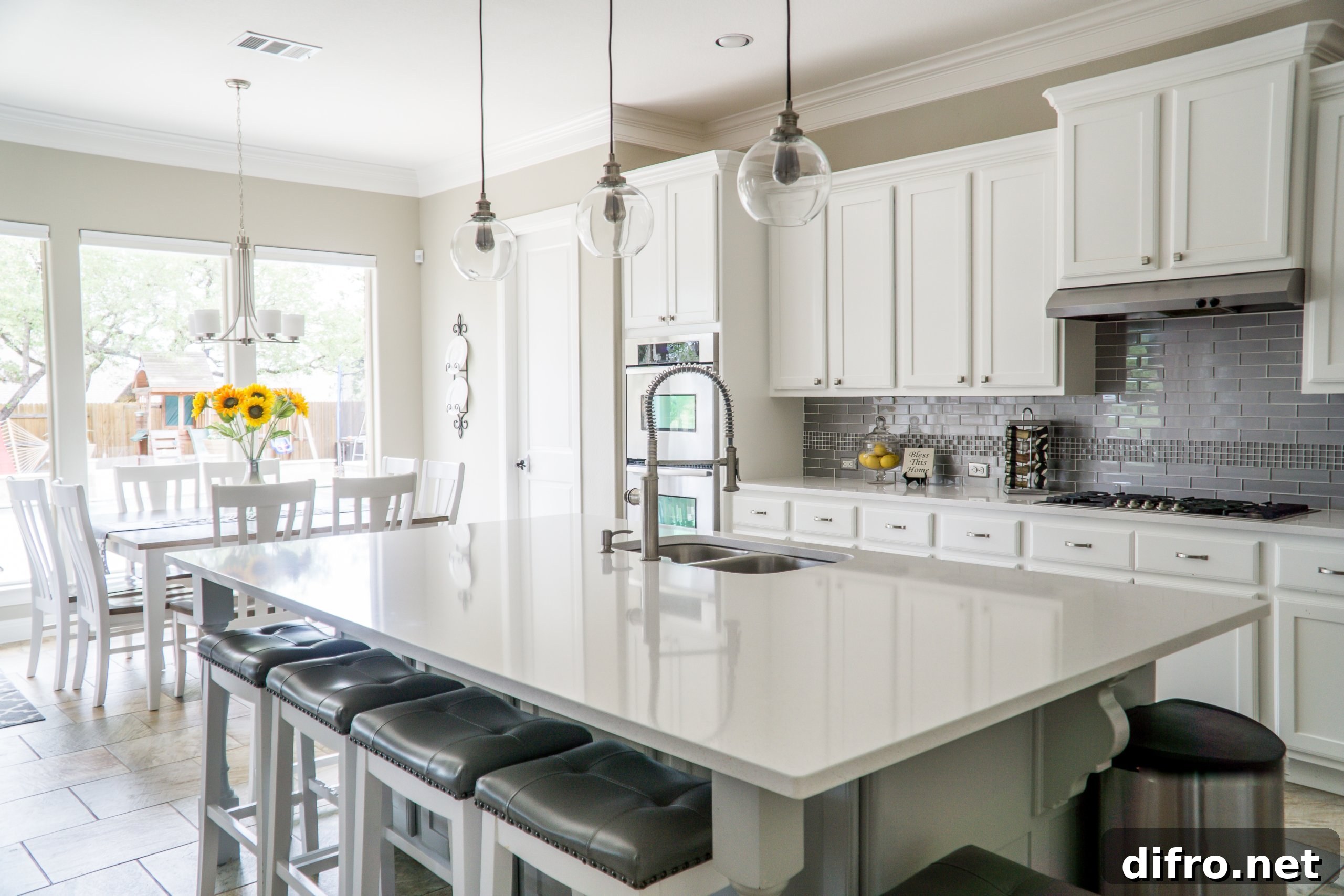 Kitchen interior with white cabinets, large island and white dining table and chairs