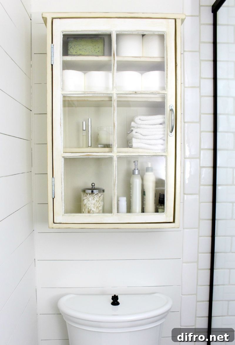 Old white cabinet full of things above toilet
