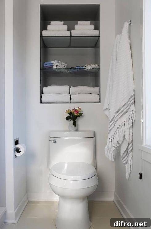 bathroom with white toilet built in shelves over toilet with white towels turkish towels hanging on wall