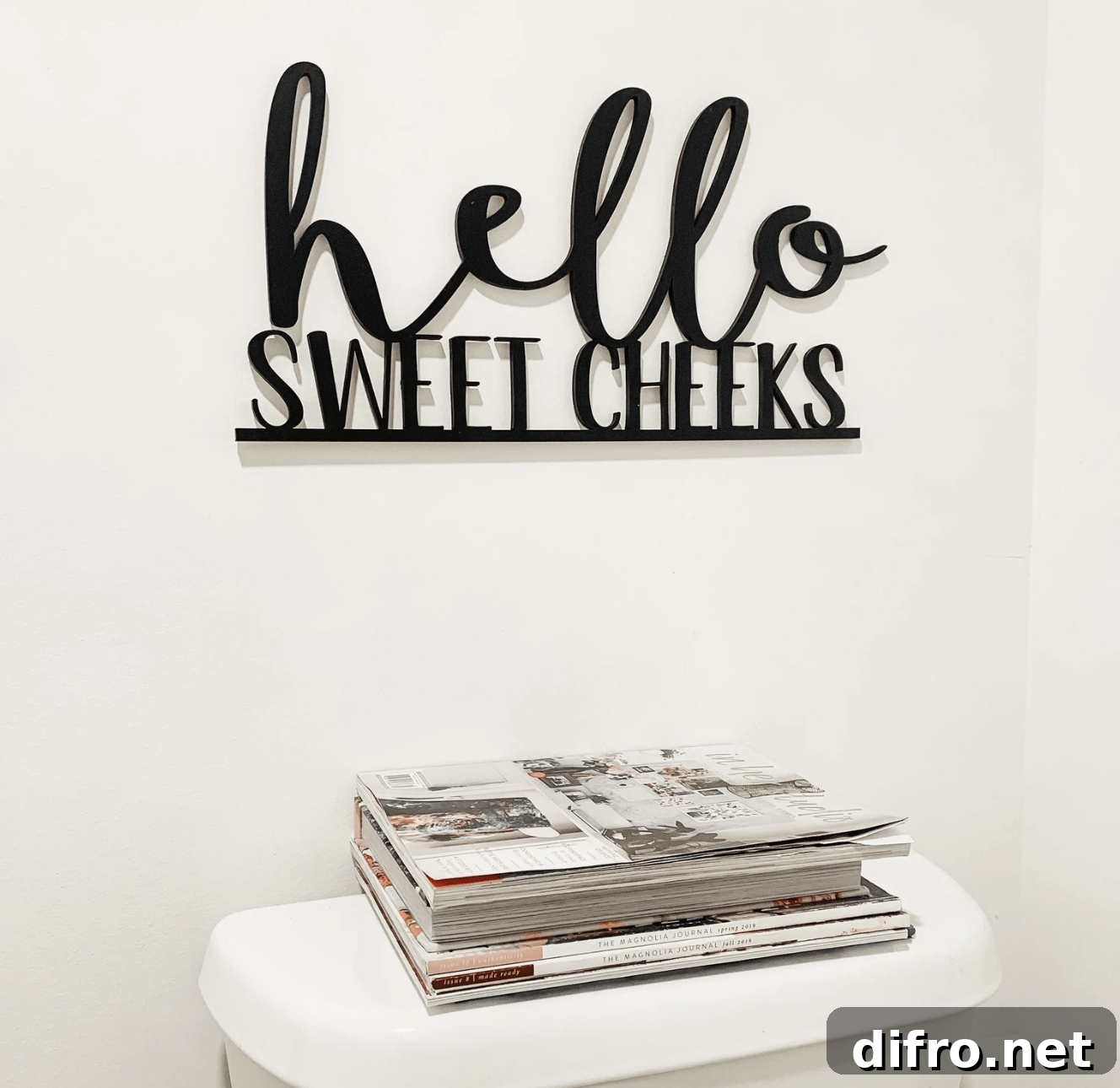 hello sweet cheeks black iron cut out bathroom sign hanging over toilet stack of magazines
