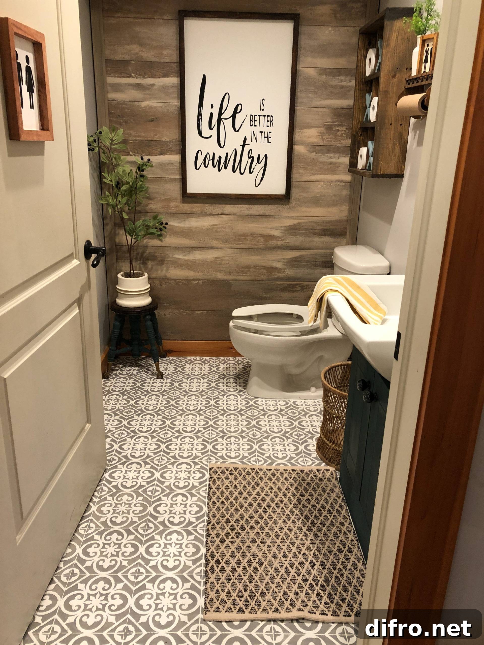 country bathroom farmhouse wood accent wall stenciled tile floor toilet greenery sign