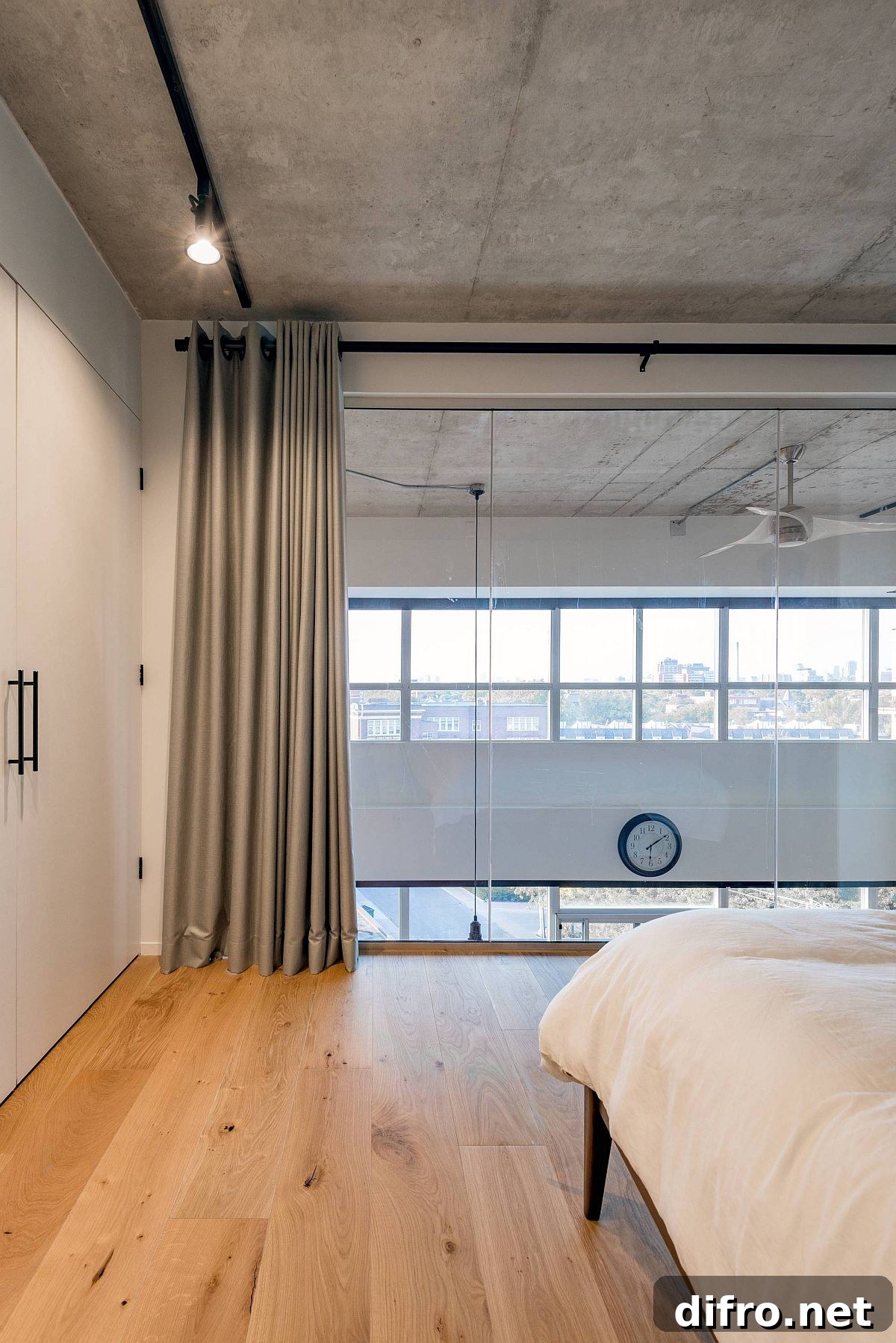 Modern bedroom with wooden floor, concrete ceiling and gray drapes